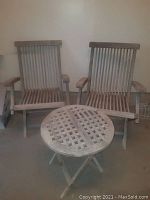 Pair of wooden folding patio chairs and round table against wall