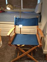 Single blue canvas folding producer chair with wooden frame, shown from front.