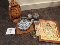 Lot displayed on carpet including clay incense jar, ceramic teapot on tray, small jars, paper prints and card.