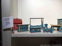 Photo of various pieces of dollhouse furniture including dresser, bench, small bed, and table, all hand painted with floral designs.