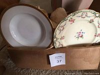 View of soup bowls and floral plates stacked in a cardboard box