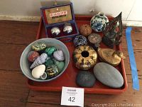 Full view of all items on orange tray showing variety of decorative items including stones, metal balls, vase, figurine