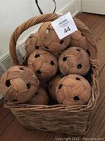 Front view of the woven basket filled with the 12 woven rattan spheres showing handle and basket size
