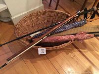 Basket with umbrellas and walking sticks inside.