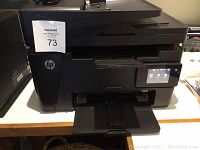 Front view of HP LaserJet Pro MFP M127fw printer showing paper output tray and touchscreen.