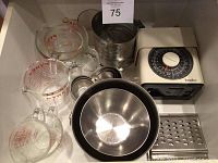 Photo showing Pyrex glass measuring cups in 4-cup, 2-cup, and 1-cup sizes, metal mixing bowls, Terraillon kitchen scale, metal sifter, and metal grater in white box.