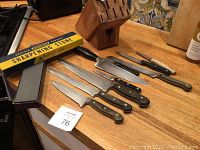 Overview of six knives lined front, wooden block, sharpening stone and box