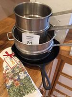 Griswold cast iron skillet stacked with Vollrath and All Clad double boilers alongside two new floral dish towels