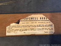 Close-up of label on black slate cheese tray showing Harpswell House brand and details about the material and finish.