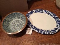 Blue and white Ralph Lauren meat platter with floral trim and round blue and white serving bowl beside it, placed on wooden floor