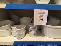 Assorted kitchenware including cups, dipping bowls, ramekins, and oval ribbed ramekin