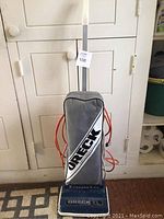Front view of the Oreck XL vacuum cleaner showing blue base, gray bag with Oreck logo, standing upright.