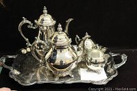 Full view of the 5-piece tea set arranged on the tray, showing the teapot, coffee pot, sugar bowl (no lid), and creamer, all silver plated with ornate detailing.