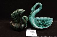 Both vintage Blue Mountain Pottery swan figurines, candy dish and winged vase, shown side-by-side on black background.