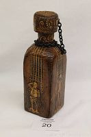 Front view of the vintage rectangular leather-wrapped decanter with embossed image of a man and ornamental detailing, showing attached cork stopper and chain.
