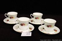 Four vintage Royal Albert floral bone china teacups with four matching saucers arranged on black background.