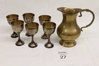 6 small brass goblets and 1 small brass pitcher displayed on a plain background.