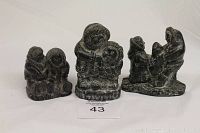 Lot of 3 soapstone Eskimo figurines standing and sitting showing detailed textures and carvings.