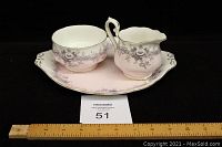 Full view of the three pieces - plate, sugar bowl, and creamer on black background showing shape and decoration