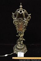 Front full view of the antique cherub table lamp showing the ornate brass base and stained glass shade with cherub figure.