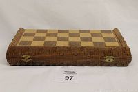 Closed wooden chessboard showing carved decorative edges and brass hinges