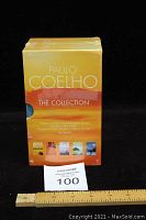 Sealed box set of Paulo Coelho's collection with a yellow-orange gradient design showing title and author name on the back panel with mini cover images.