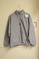 Grey Adidas Originals Paris Pack 1/4 zip pullover sweatshirt hanging on pegboard.