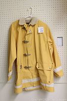 Full view of the yellow raincoat showing the toggle clasps, reflective stripes, beige collar, and large pocket.