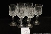 Seven D'Arques 'Longchamp' crystal wine glasses arranged in rows on a black background to display faceted design and stem shape.