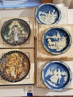 Side-by-side view of five Bradford Exchange Christmas plates, showing various illustrations and decorative borders, some plates on boxes.