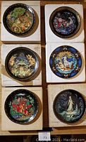 Six Bradford Exchange decorative collectible plates on white boxes, showing colorful folklore scenes with ornate borders.