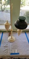 Front view of white painted brass kerosene lamp converted to electric with green ribbed glass shade on side.