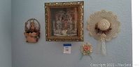 Wall display of vintage 3D cardboard cutout basket in shadow box, two crochet hats, and additional floral wall hangings.
