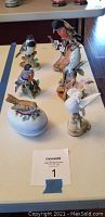 Seven bird figurines displayed on a table, showing overall lot contents.