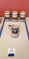 Four Budweiser beer steins with winter and horse-drawn carriage scenes on table