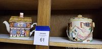 Side view of Sadler Country Village teapot shaped as a cottage and ceramic canister with dancing couple, both on shelf.