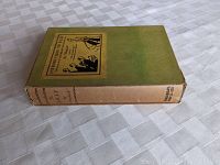 Top angle view of the book showing the spine with title, author name, and publisher. The book is covered with a dust jacket and placed on a white textured surface.