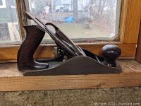 Side view of antique Bailey No. 4 wood plane on window sill.