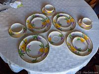 Full layout of all 15 pieces including dinner plates, dessert plates, saucers and teacups on a white tablecloth