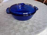 Side view of cobalt blue glass casserole dish with lid showing the round shape and side handles.