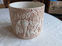 Ceramic planter showing elephant and jungle foliage relief detail on the front side.