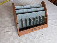 Front view of wooden and metal Cumberland Pencil Co. advertising display with multiple vertical metal compartments and a horizontal metal bar across the front. Shows printed maker's mark on front.