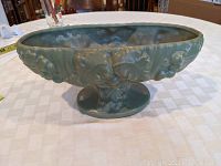 Oval footed green pottery planter showing the decorative grape and leaf relief pattern and matte glaze finish.