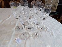 Seven clear crystal white wine glasses with cut Petite Points pattern on round steel table.
