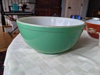 Side view of vintage Pyrex primary green mixing bowl showing the smooth rounded shape and glossy green exterior with white interior.