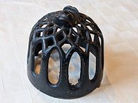 Top angle view of the black cast iron string holder showing dome shape with open lattice design and a knob at the top.