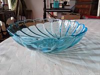 Side and slightly angled view of the blue glass fruit bowl showing swirl pattern and scalloped edge.