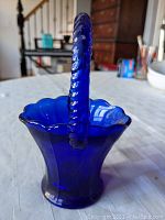 Photo showing the cobalt blue textured glass basket with scalloped rim and handle from a side angle.