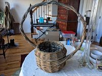 Large grape vine hanging basket with twisted handle placed on a table, showing the basket's size relative to surroundings.