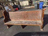 Front view of full pew showing seat, backrest and worn finish with scratches